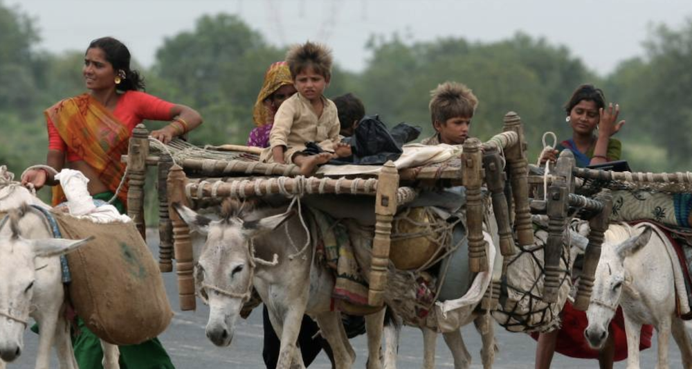 Tribal people walk with their belongings in Tarapur village, about 87 km (54 miles) south from the western Indian city of Ahmedabad July 13, 2007. REUTERS/Amit Dave (INDIA)