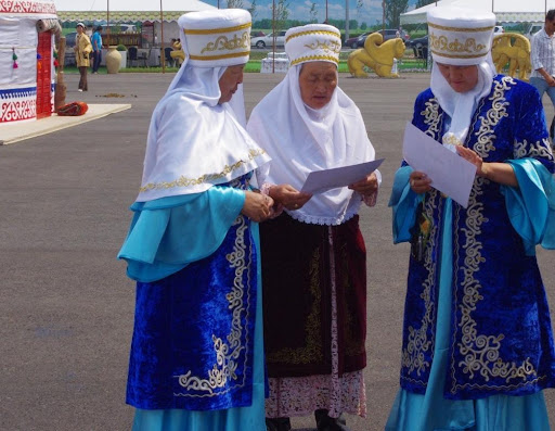 Three matrons in traditional Kazakh dress take a break from creating intricate weavings to decorate yurts, photo by Ken Fairfax, Creative Commons Attribution 2.0 Generic license